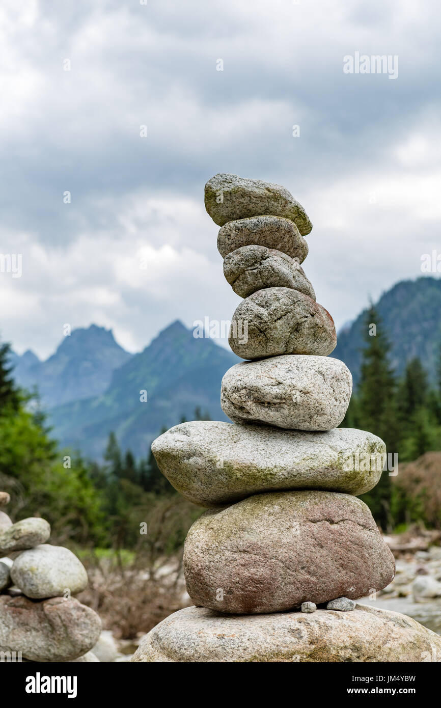 Stones balance, hierarchy stack over cloudy sky in mountains. Inspiring stability concept on rocks. Stock Photo