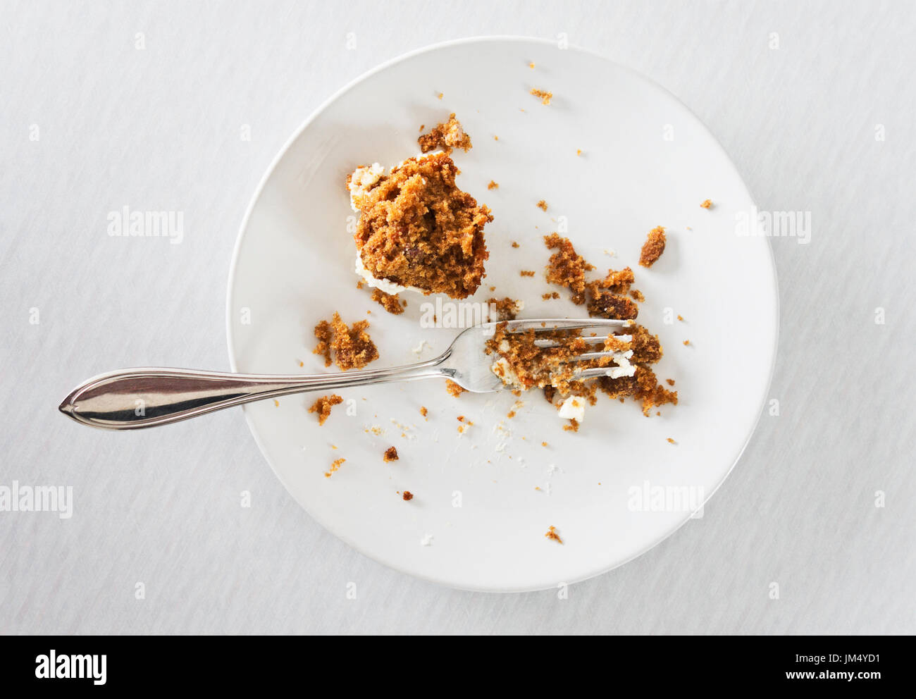 Half eaten cake on white plate with fork. Stock Photo