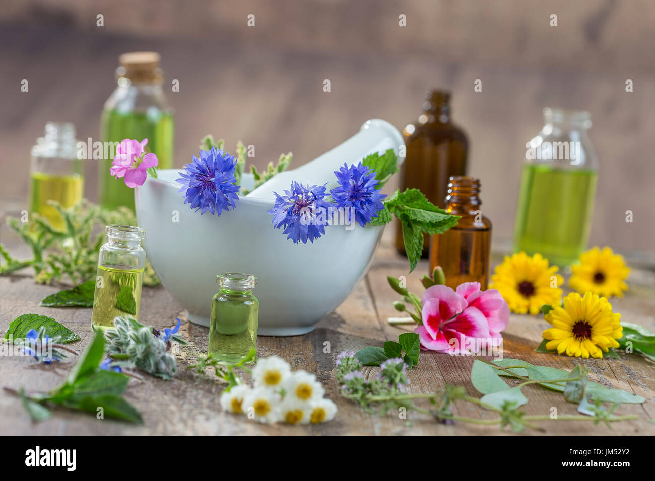 essential oils for aromatherapy treatment with fresh herbs in mortar, and essential oik bottle on the back on bleue wooden board background Stock Photo