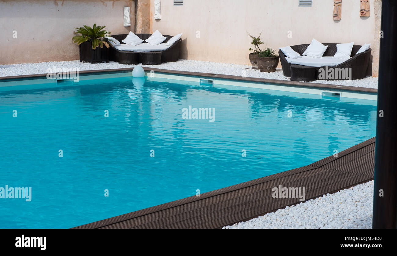 Lounge sofas in the pool with Bankirai and white pebble Stock Photo