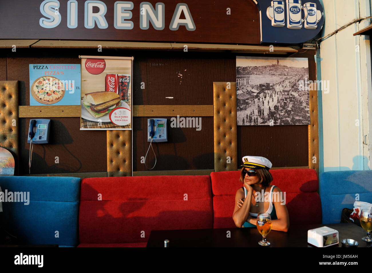 TURKEY Istanbul, woman with captain hat drinks Efes beer in Pub under bridge over Golden Horn/ TUERKEI Istanbul, Frau mit Kapitaens Muetze trinkt Efes Bier Stock Photo