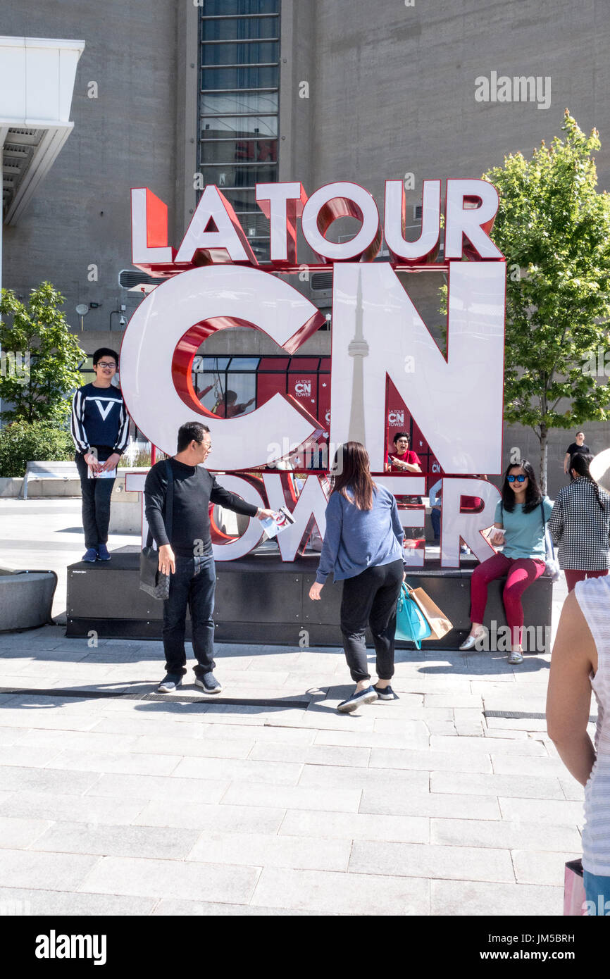 Tourists posing at the CN Tower sign in downtown Toronto Ontario Canada Stock Photo
