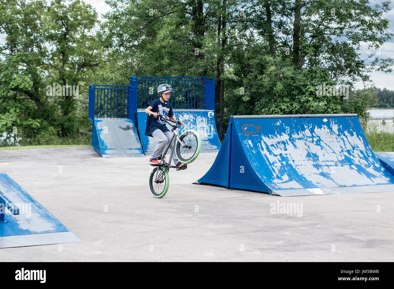Teenage boy doing tricks popping a wheelie on bicycle during BMX