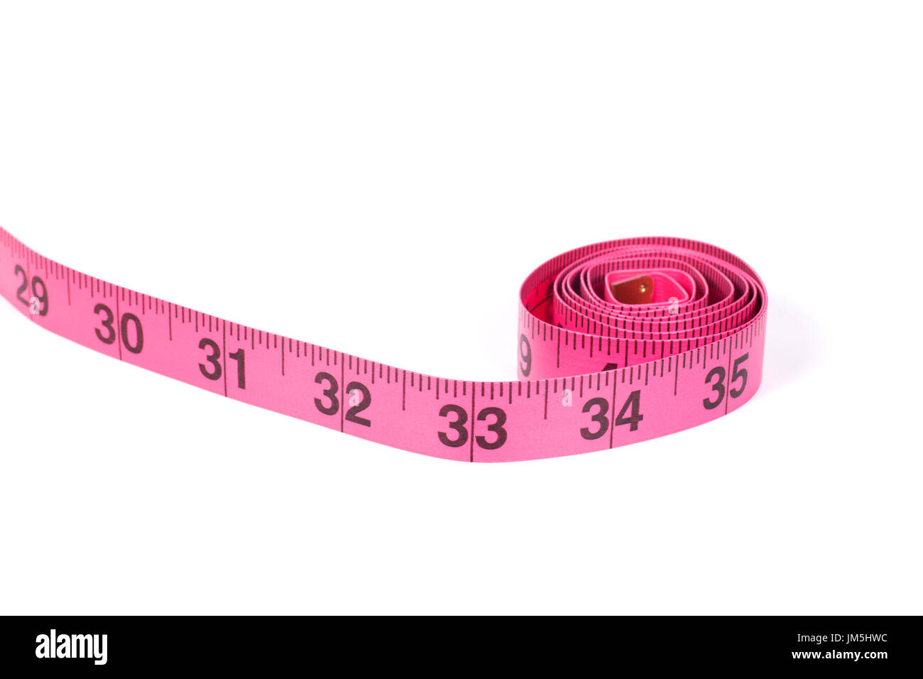 Pink measuring tape roll marked in inches with one end going outside the frame, close-up isolated on white background with copy space Stock Photo