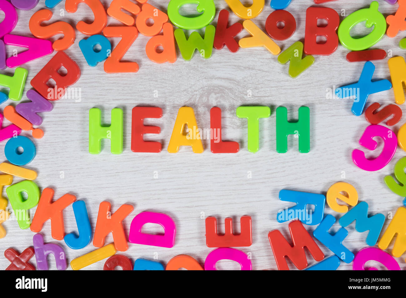 Plastic magnet letters in bright colors make border around the word health against a painted wood background Stock Photo