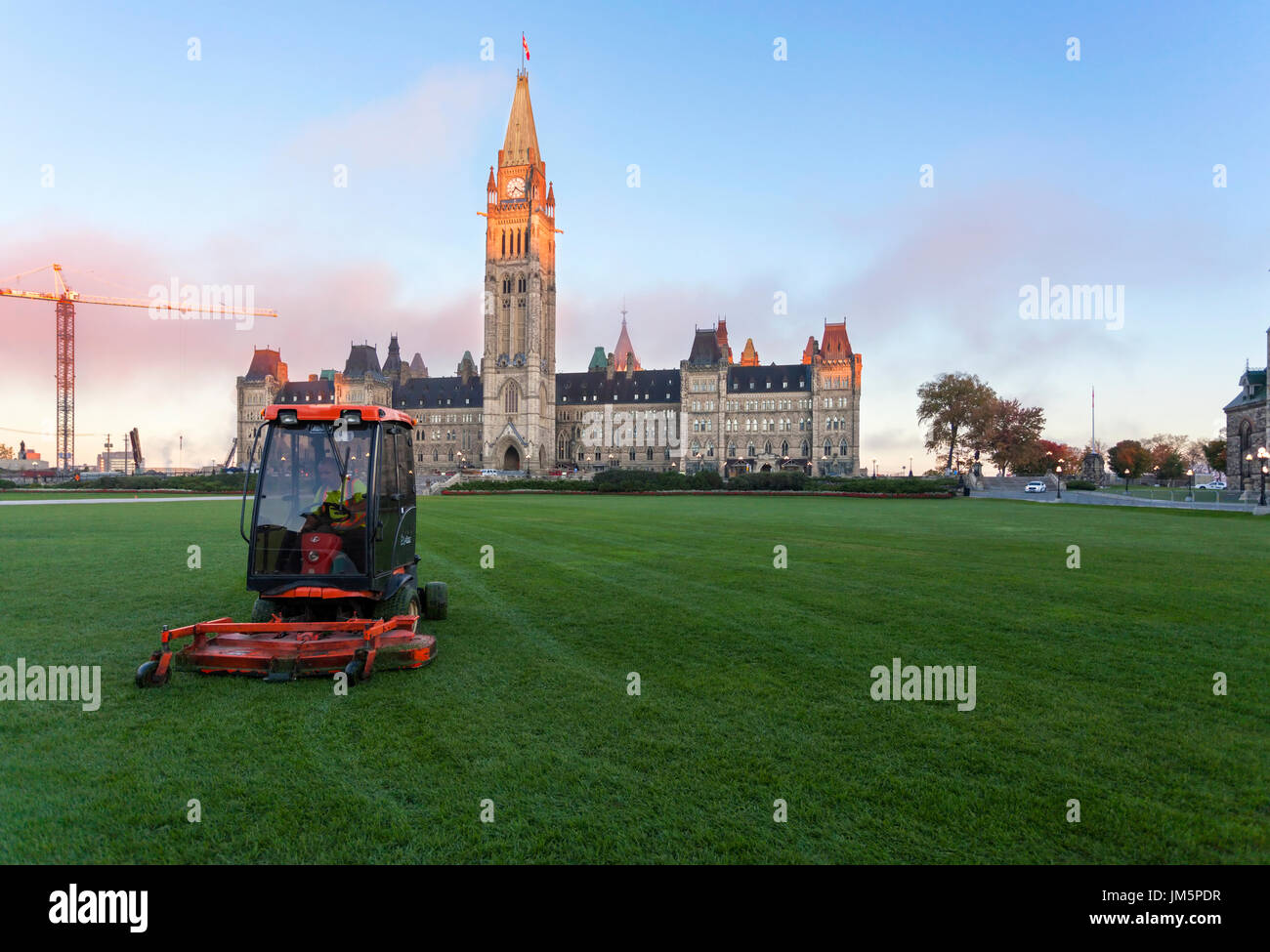 A groundskeeper mowing the lawn in front of Parliament Hill and Centre Block on a riding lawnmower in Ottawa, Ontario, Canada. Stock Photo
