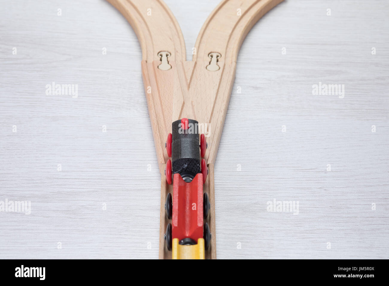 Colorful wooden toy train on a railway track viewed from above as it