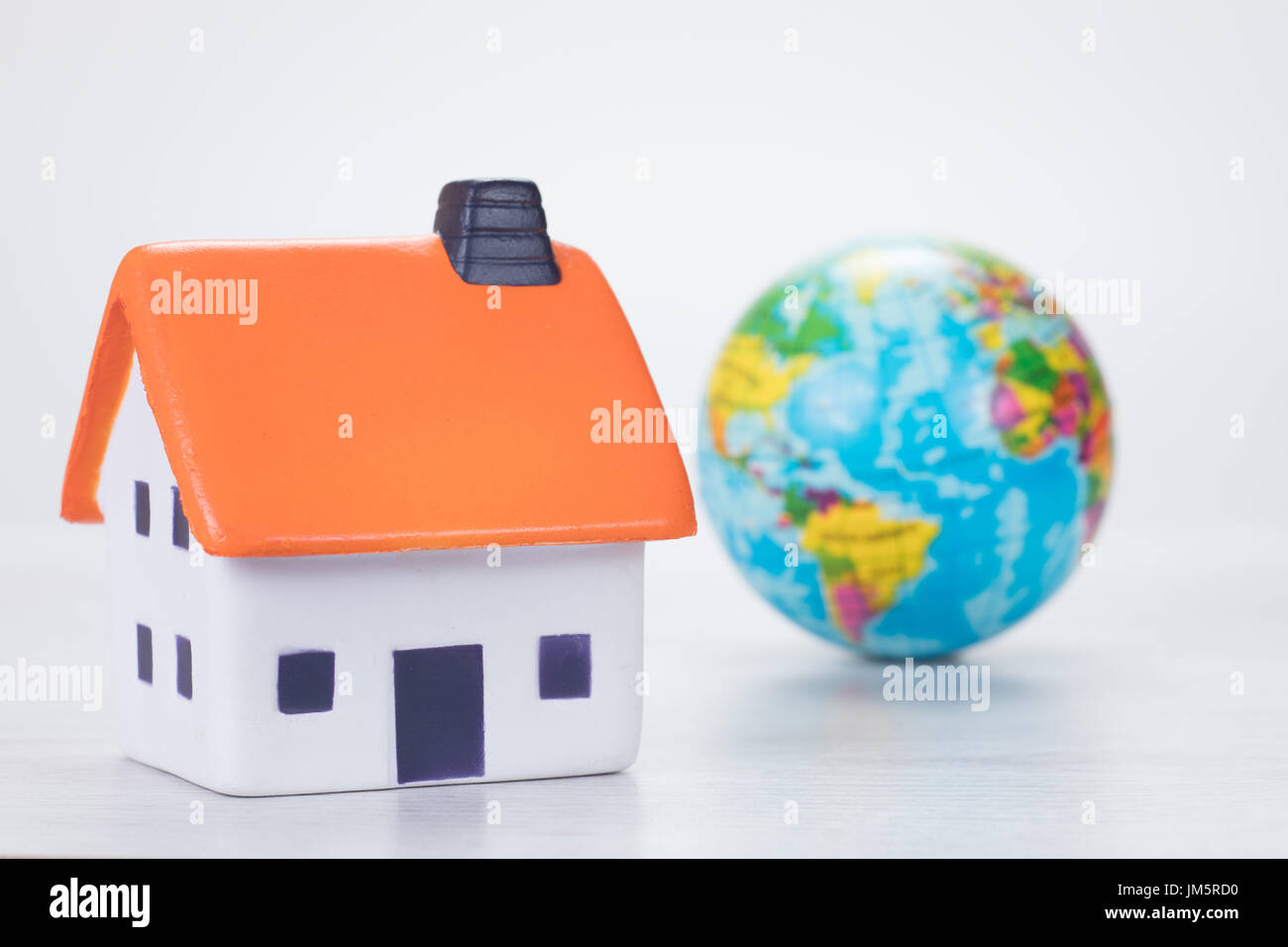 Eco-friendly efficient household energy and fuel concept with a world globe alongside a toy model over a white background to save the planet Stock Photo