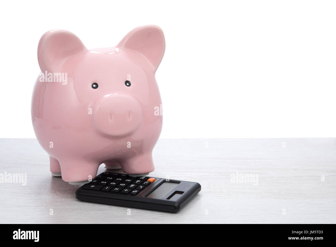 Glossy ceramic pink piggy bank with black calculator on table surface ...