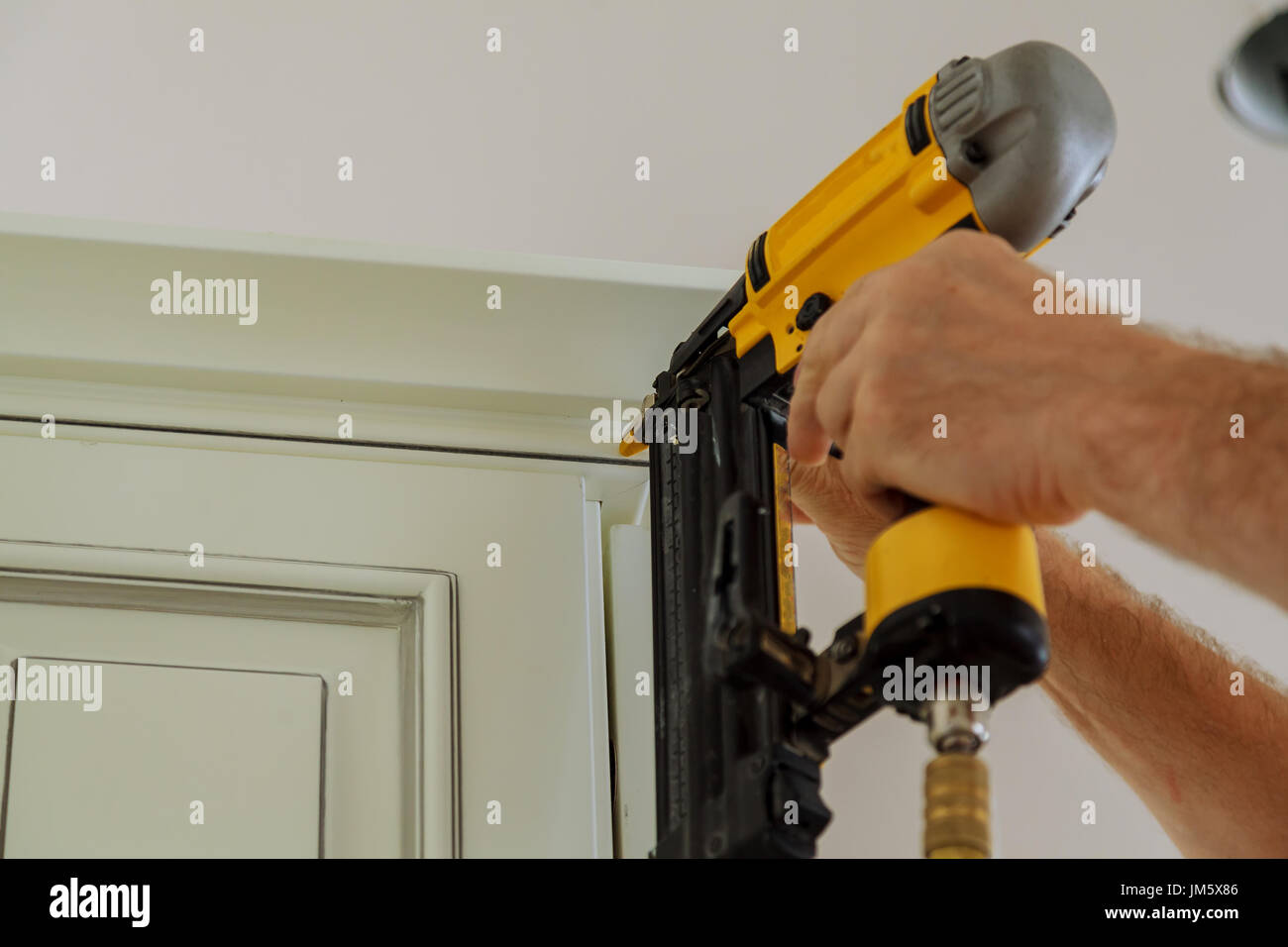 Carpenter brad using nail gun to Crown Moulding on kitchen