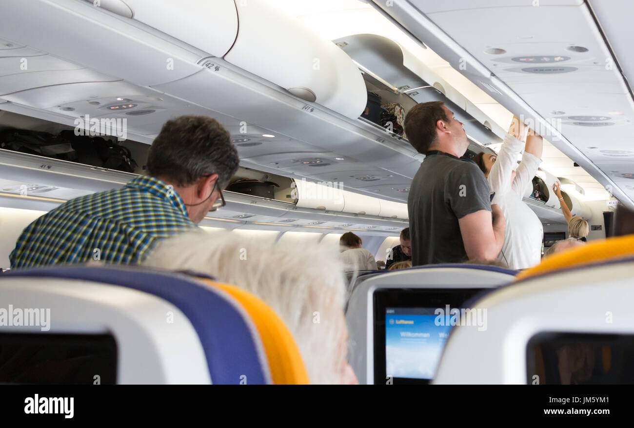 Munich, Germany - July 16, 2017: Passengers are taking off their luggage from the overhead compartment of an Airbus 330 - 300, Lufthansa Airlines. Stock Photo