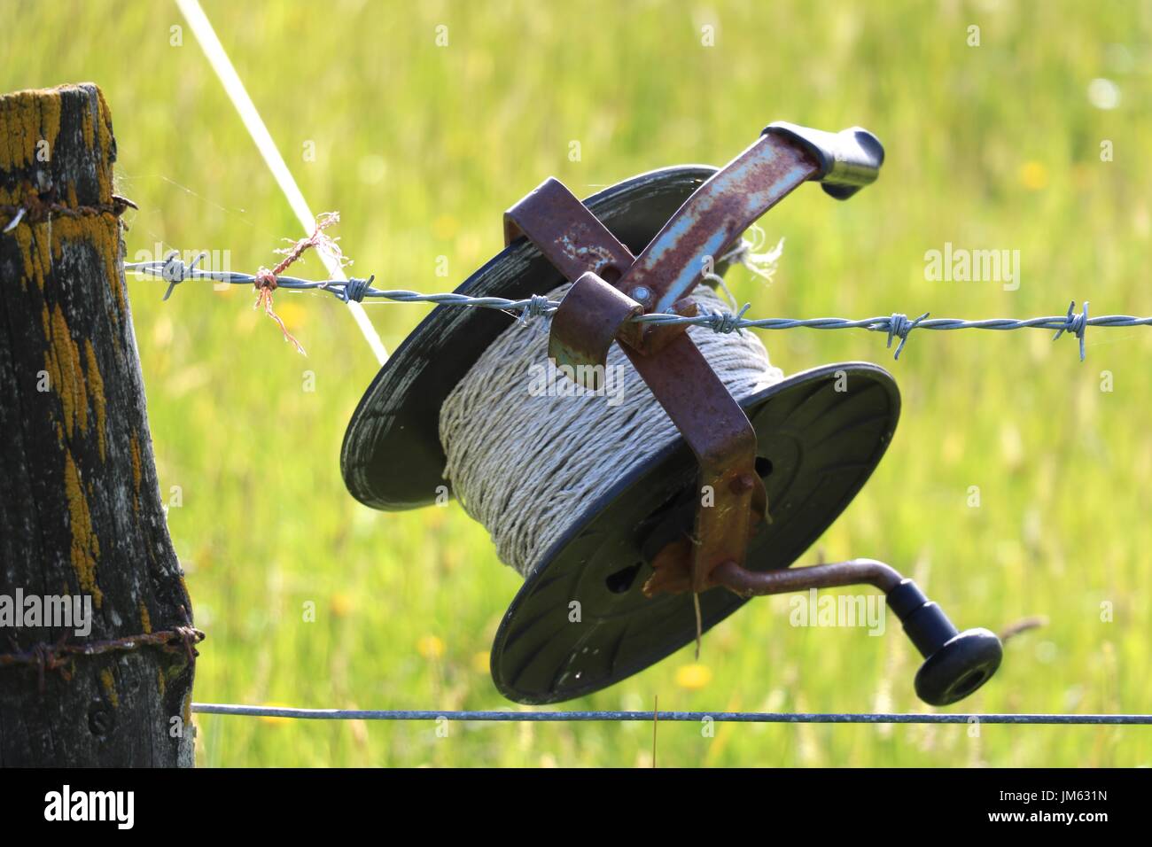 Roll of electric fence tape hooked to fence Stock Photo - Alamy