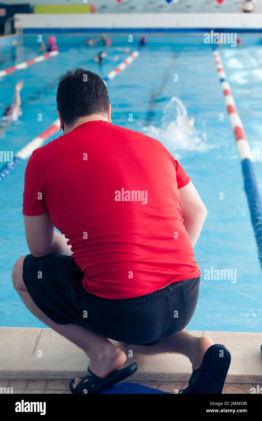 Swimming Kids Lesson red tshirt coach close to poolside Stock Photo
