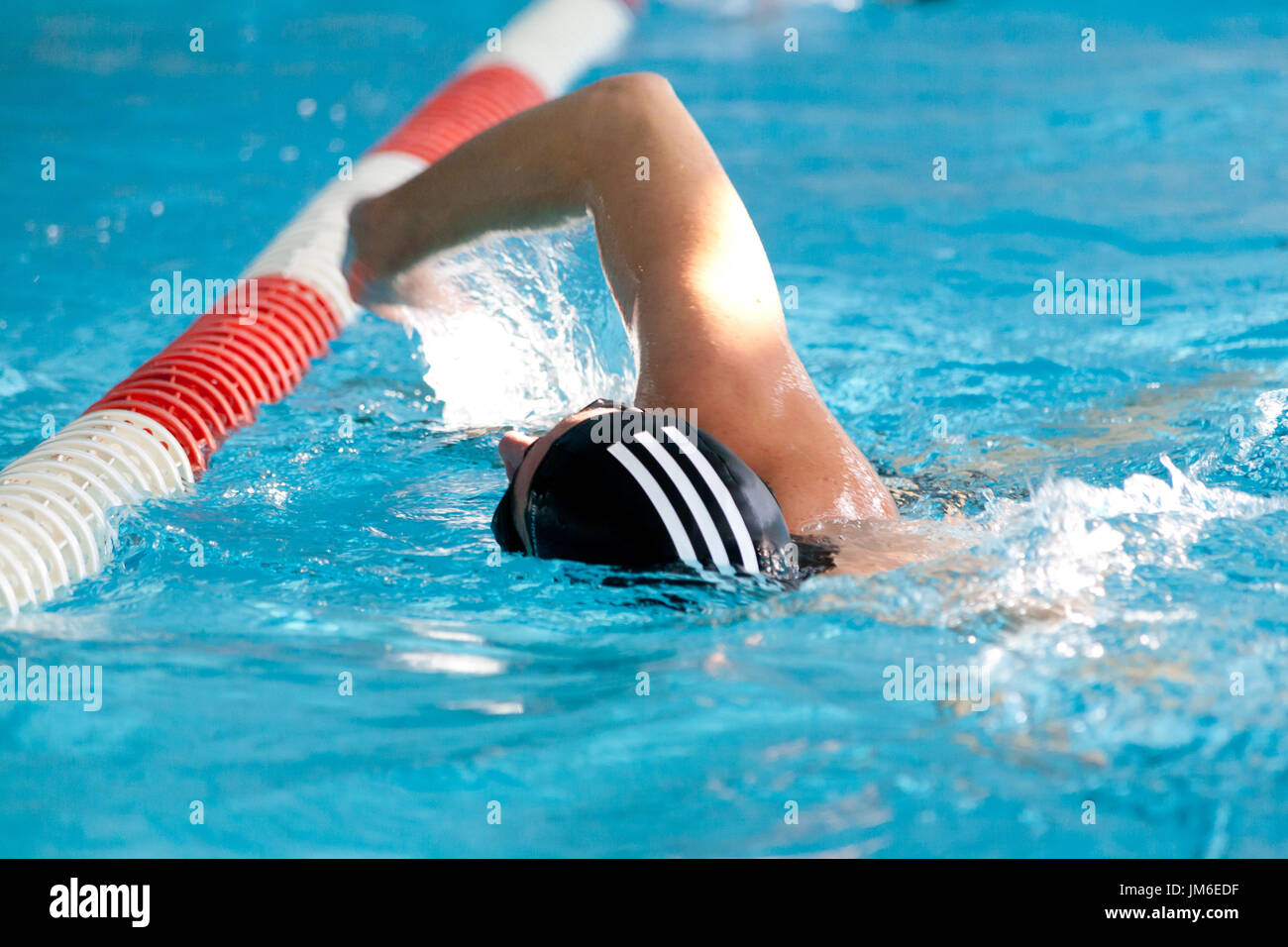 Swimming Man with black and white swimming cap close to floats Stock Photo