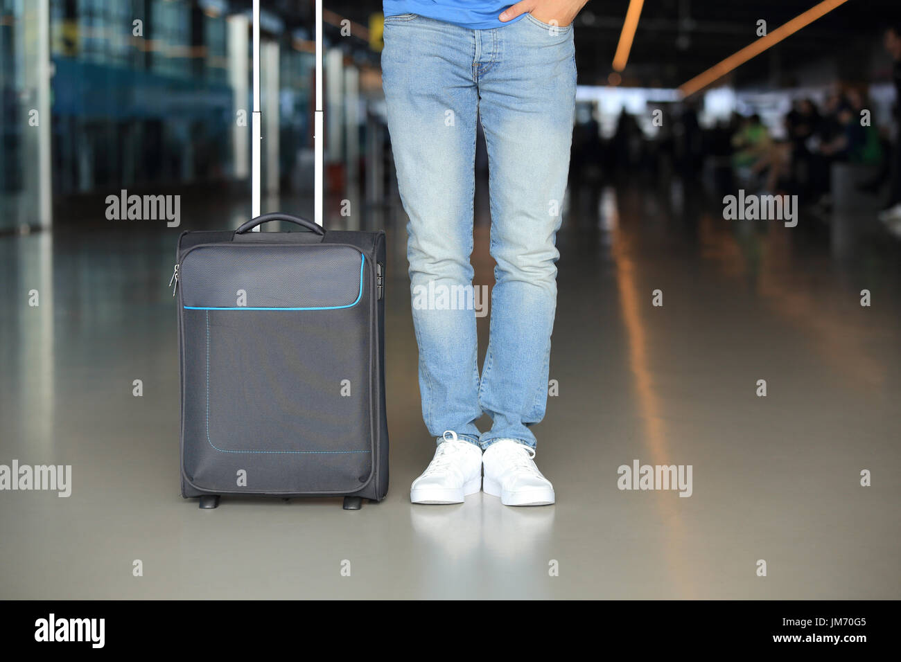 Man in blue jeans with suitcase in airport. Passenger traffic theme. Stock Photo