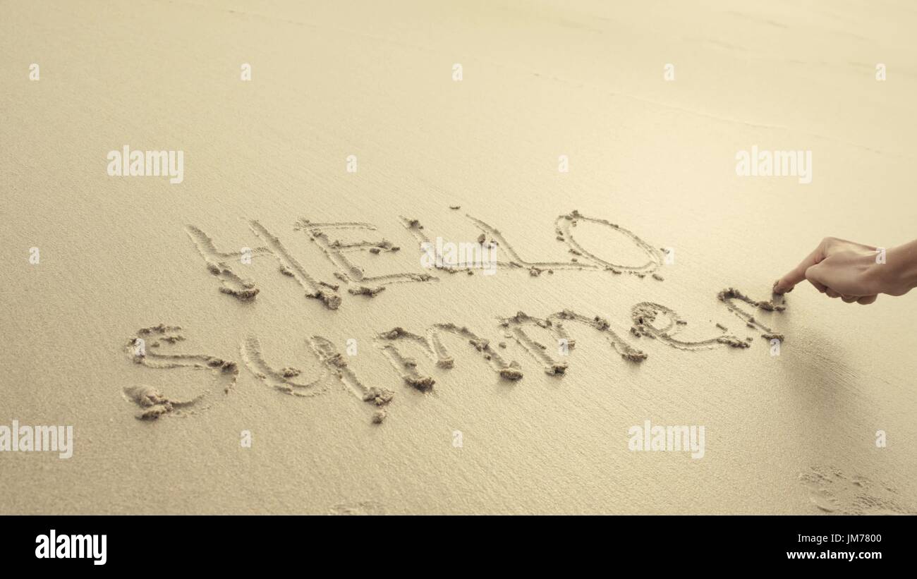 HELLO SUMMER written on the beach sand washed aways by waves. Stock Photo