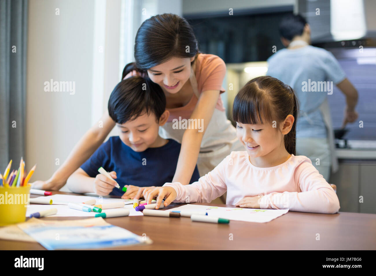 Happy Chinese siblings drawing pictures together at home Stock Photo