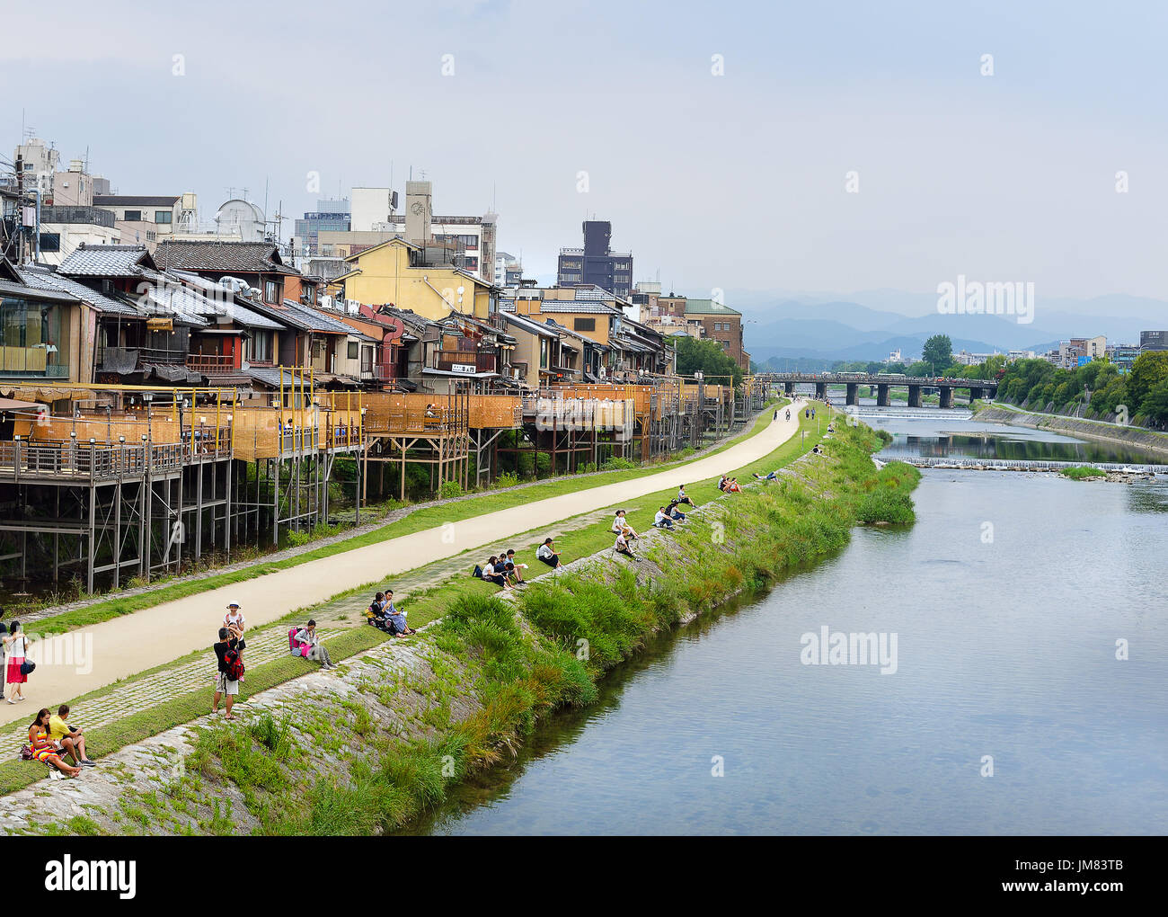 KYOTO, JAPAN - July 24, 2017: As afternoon turns to evening, couples sit on the banks of the Kamo River in Kyoto, Japan Stock Photo