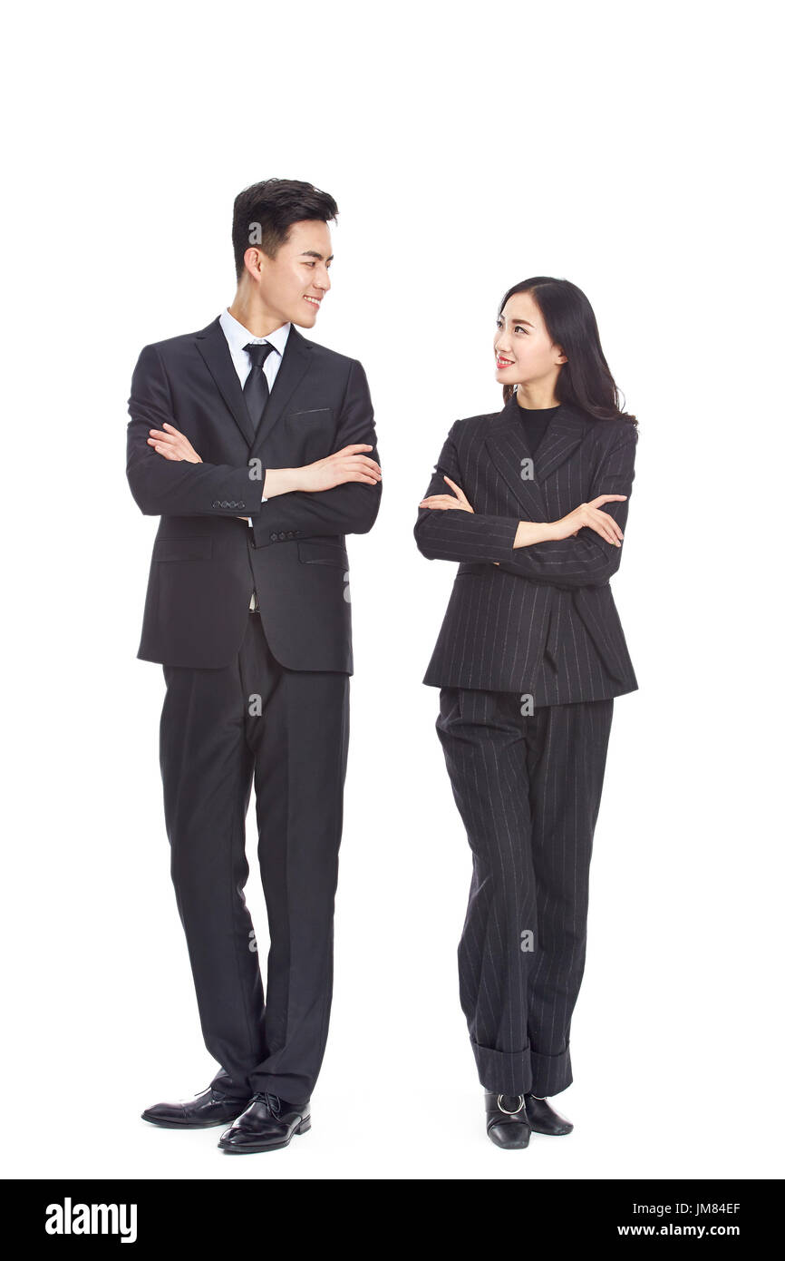 studio portrait of young asian business man and woman, arms crossed, looking at each other smiling, isolated on white background. Stock Photo
