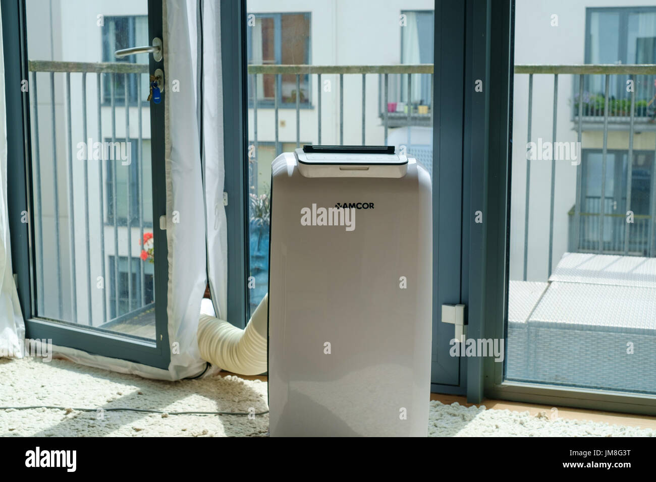 Portable air conditioning unit vented onto balcony in city flat in London Stock Photo
