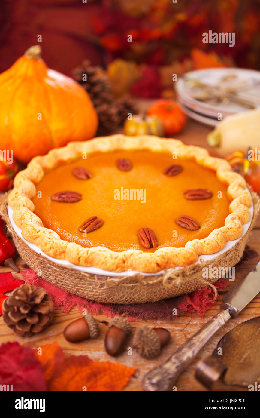 Homemade pumpkin pie on a rustic table with autumn decorations. Stock Photo