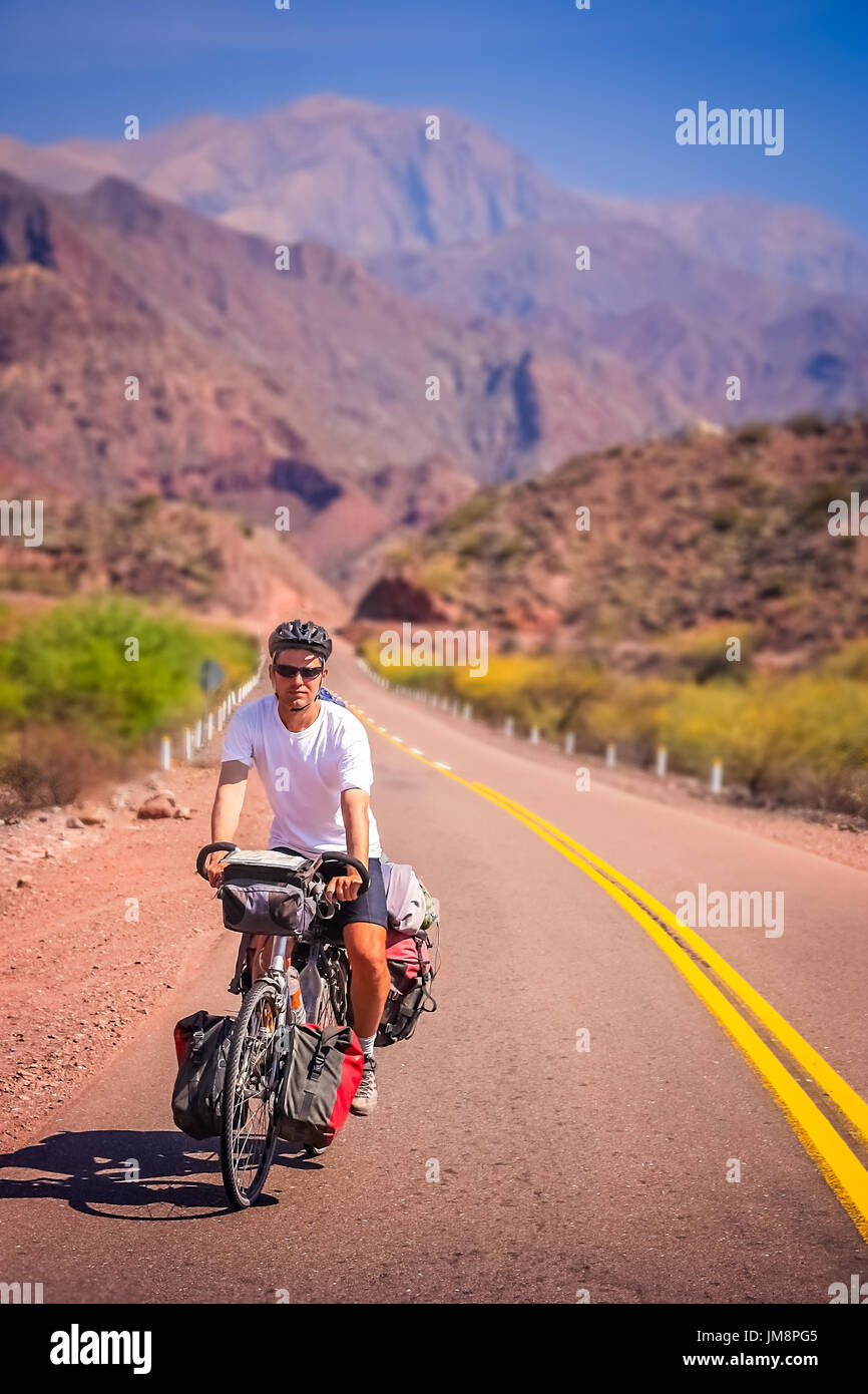 Man cycling on the empty road to Cafayate in the remote part of north west Argentina Stock Photo