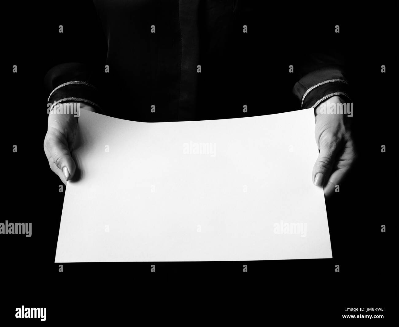 Black Mania. female hands isolated on black showing blank paper sheet Stock Photo