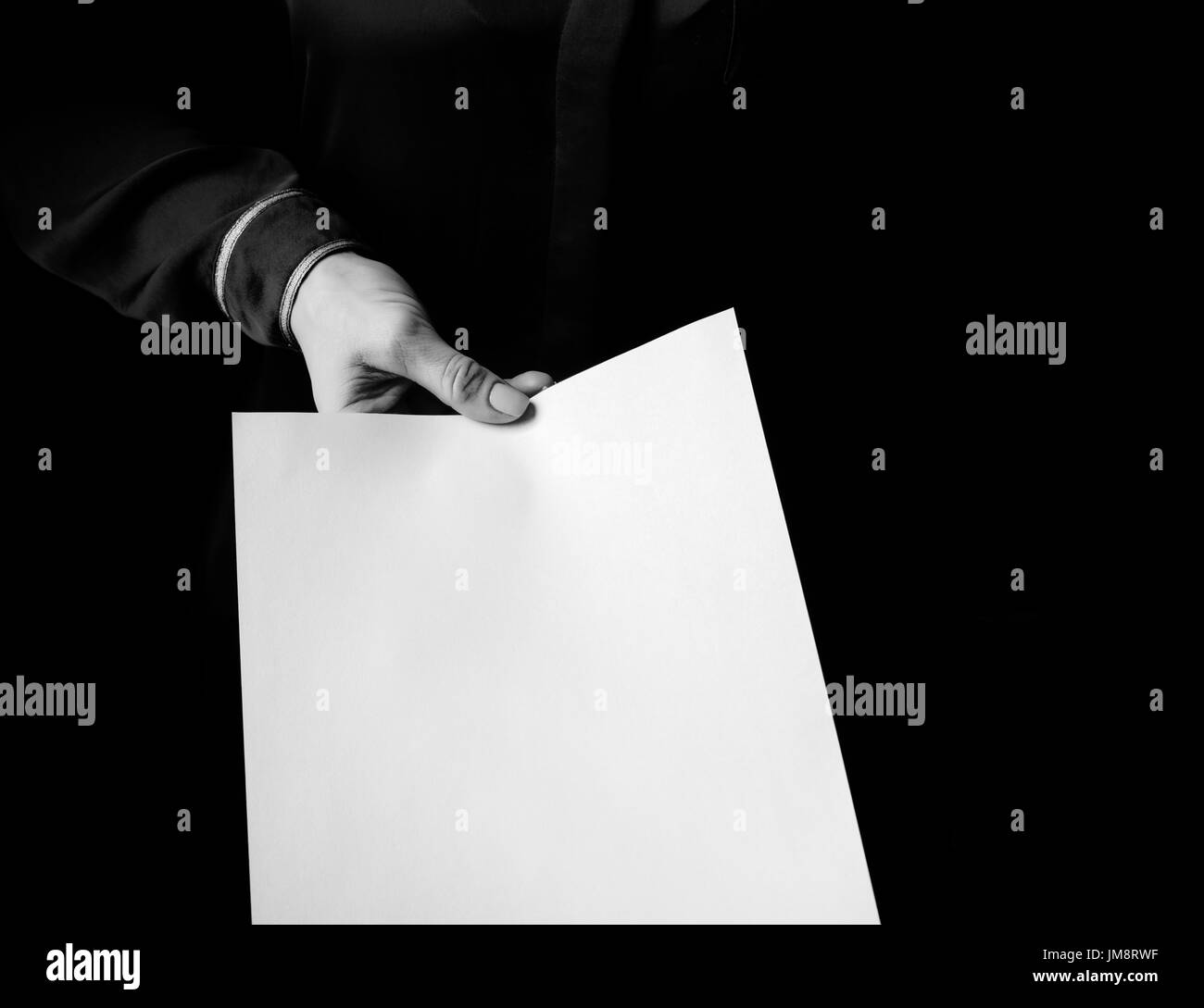 Black Mania. female hand isolated on black background giving paper sheet Stock Photo