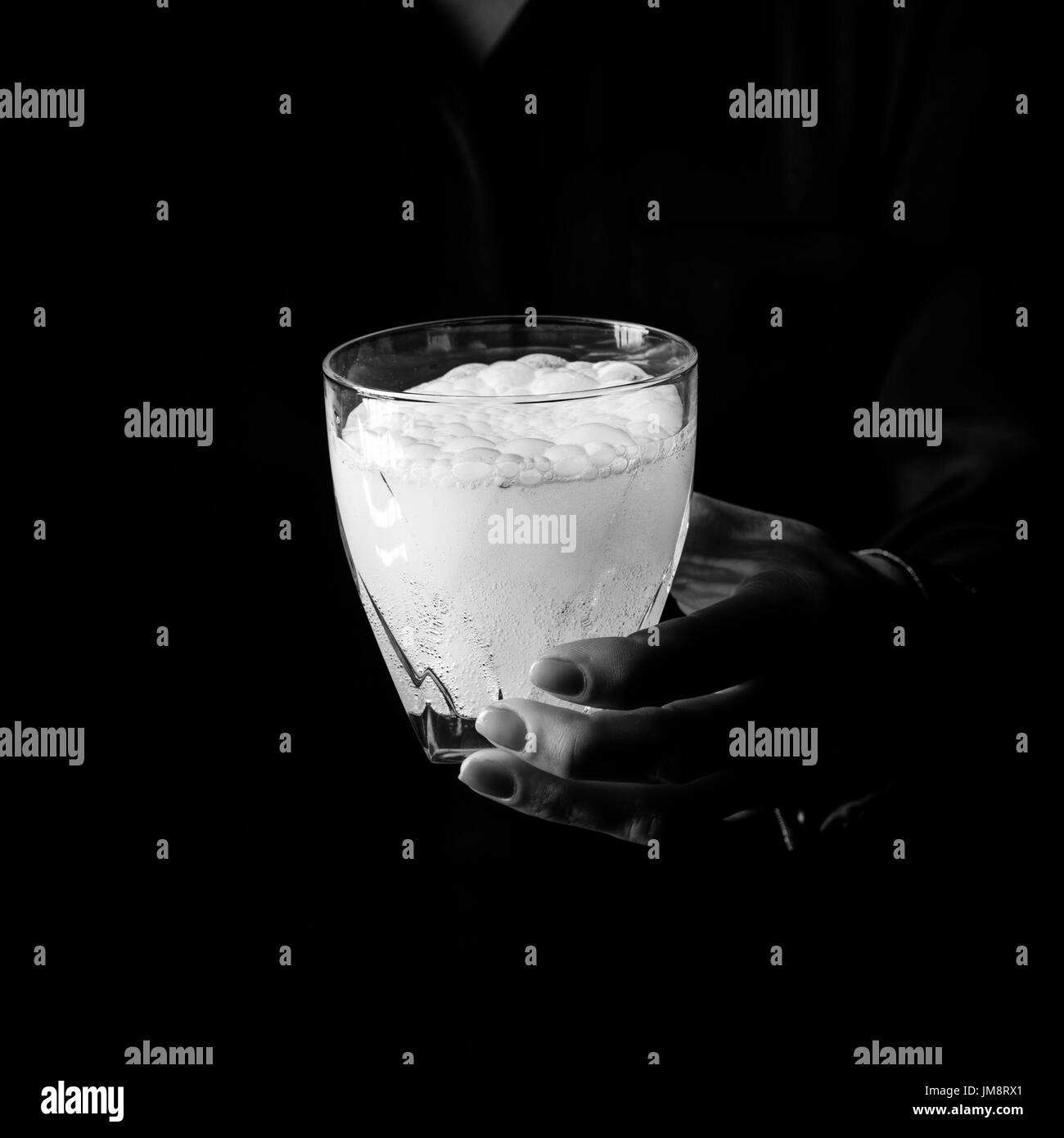 Black Mania. woman hand isolated on black background showing glass of water with effervescent tablet Stock Photo