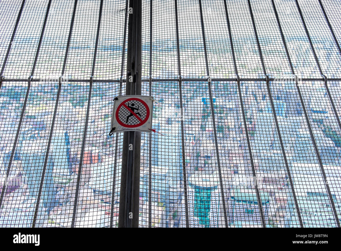 Warning Do Not Climb or Climbing Prohibited sign ideogram ideogramme on metal mesh, CN Tower viewing platform. Downtown Toronto is seen through mesh. Stock Photo