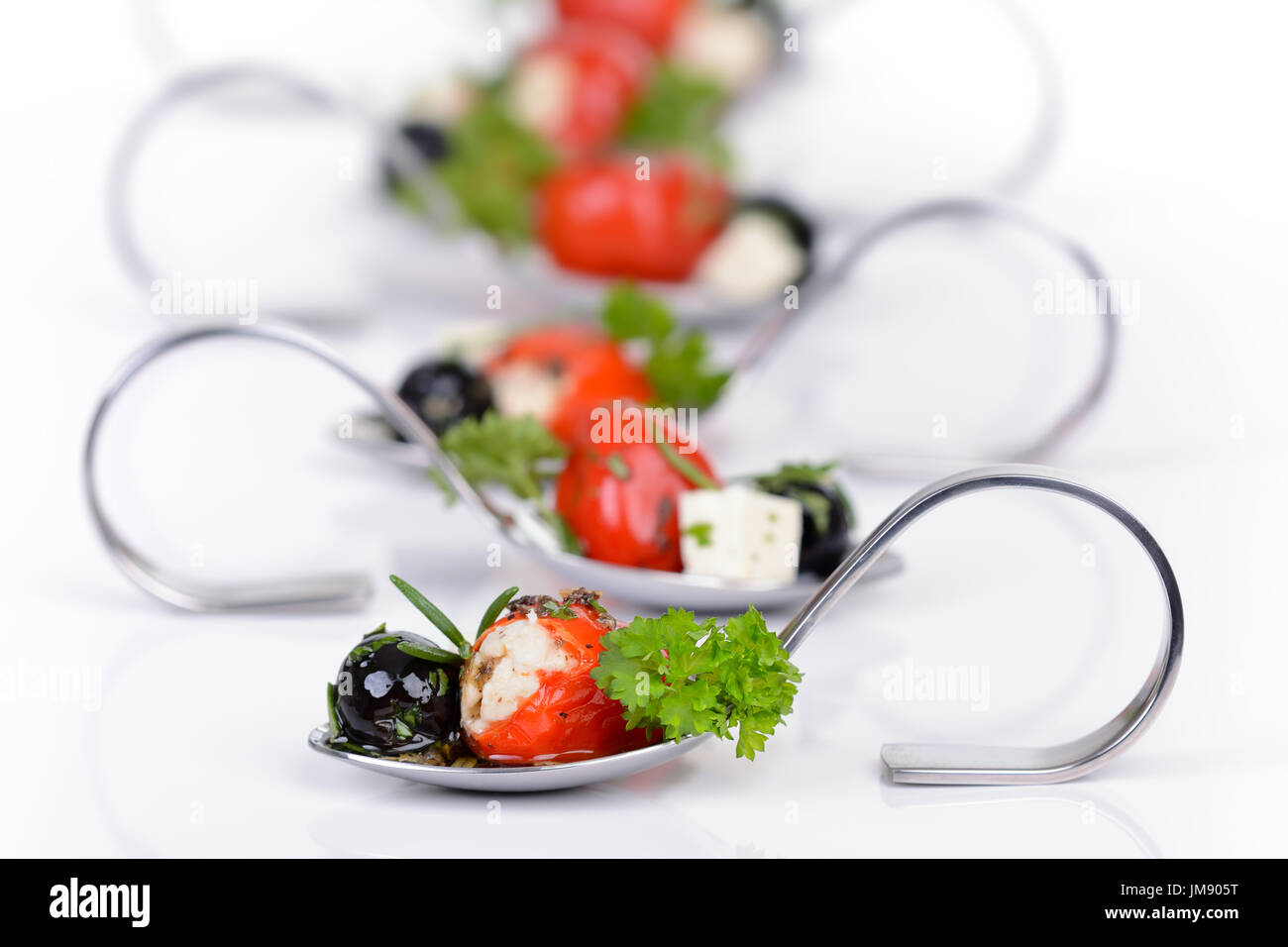Stuffed hot cherry peppers, black olives and feta cheese on decorative appetizer spoons Stock Photo