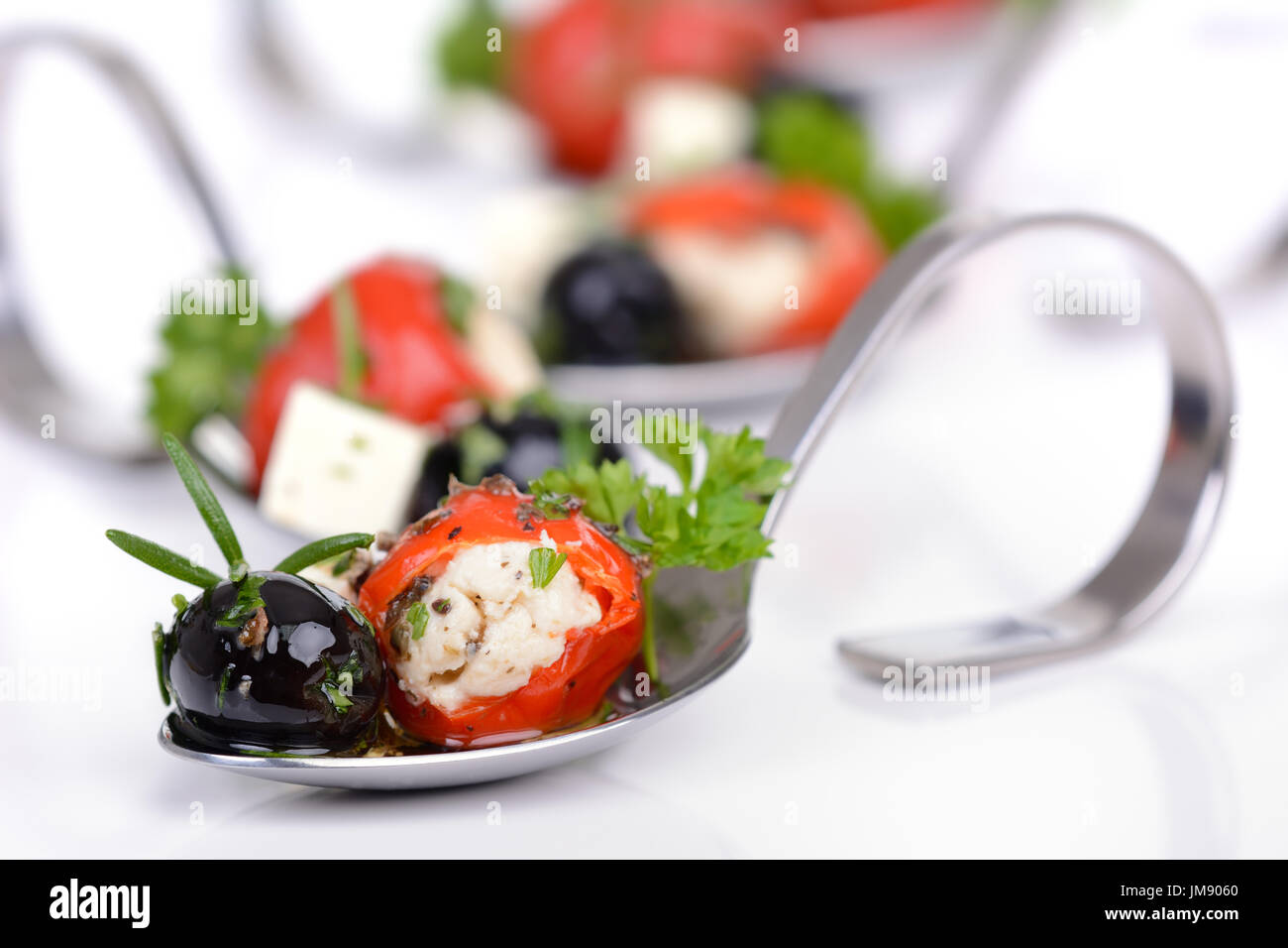 Stuffed hot cherry peppers, black olives and feta cheese on decorative appetizer spoons Stock