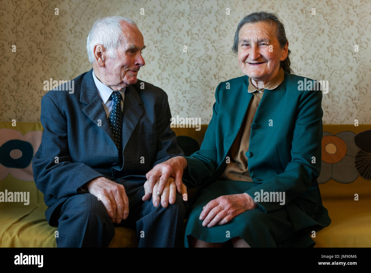 Cute 80 plus year old married couple posing for a portrait in their house. Love forever concept. Stock Photo
