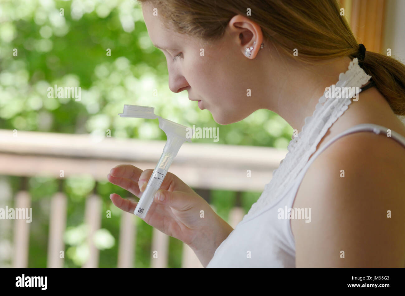 Girl collecting saliva for a mail-in DNA gene testing kit for ancestry and health genes Stock Photo