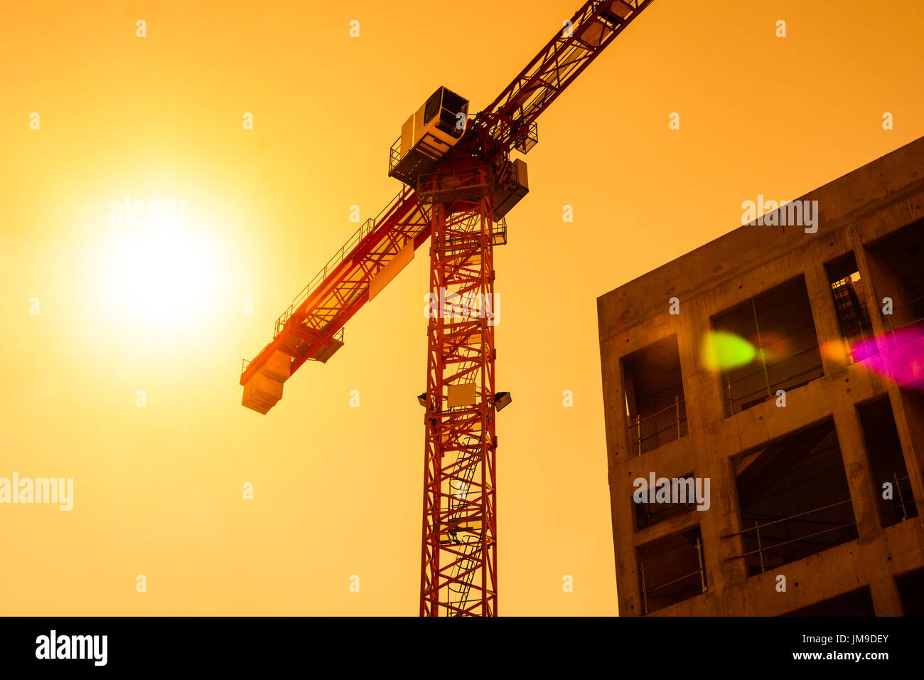 Low angle view of a tower crane next to a concrete building under ...