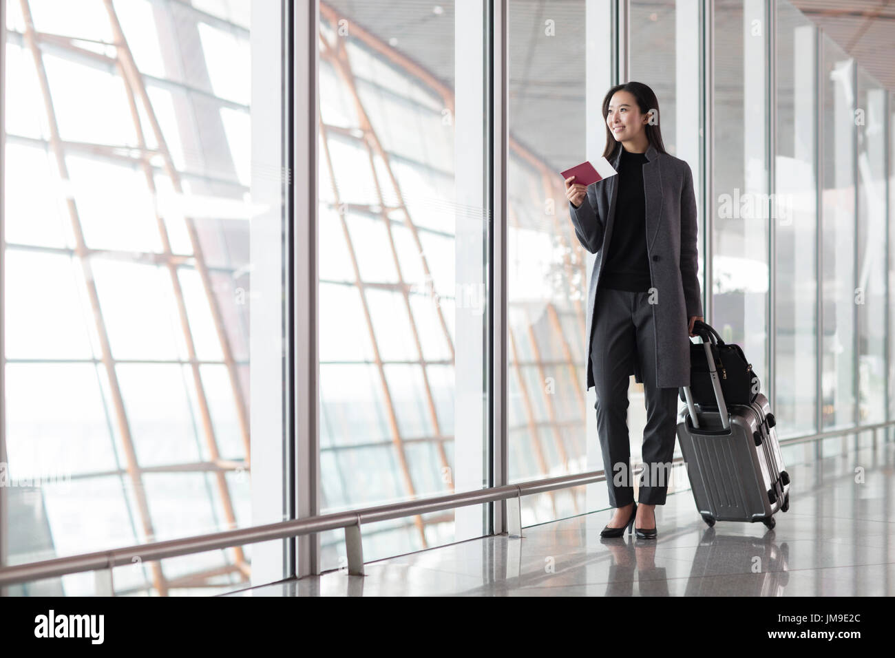 Chinese businesswoman with wheeled luggage in airport lobby Stock Photo ...