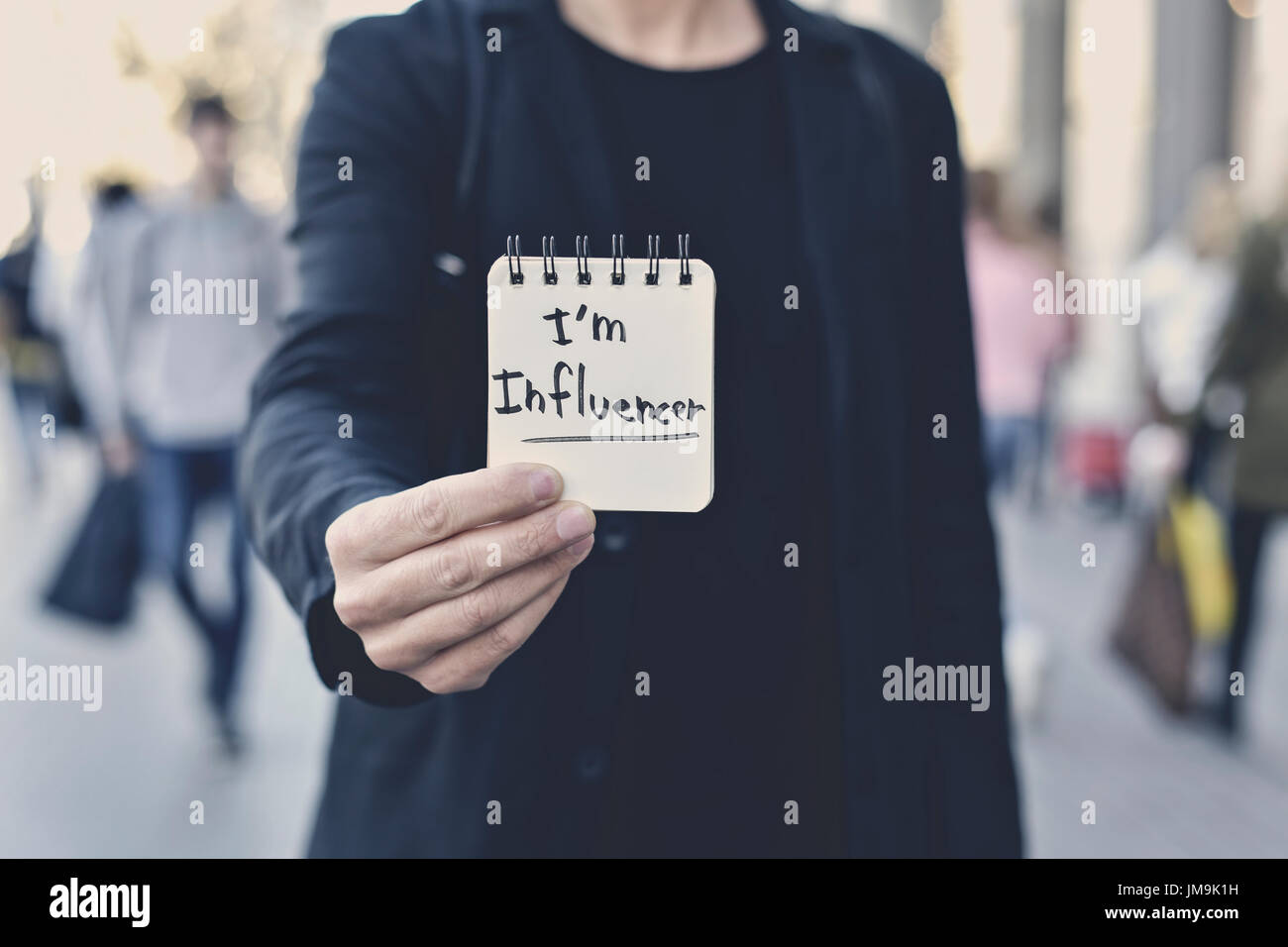 closeup of a young caucasian man in the street showing a spiral notepad with the text I am influencer written in it Stock Photo