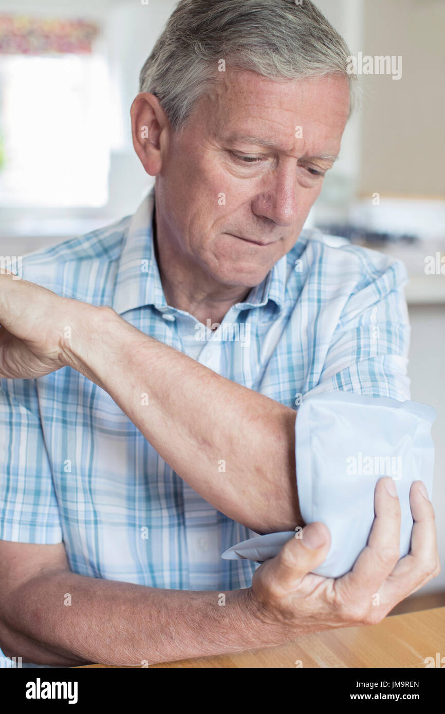 Mature Man Putting Ice Pack On Painful Elbow Stock Photo