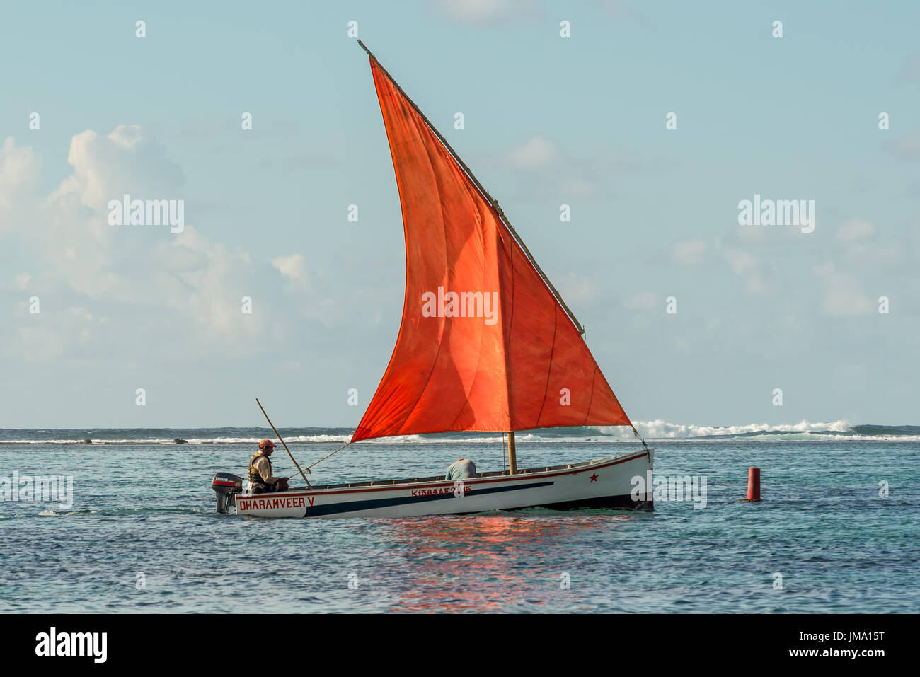 Blue Bay, Mauritius - December 28, 2015: The romantic boat with scarlet sail in Indian Ocean - Beautiful sea scene in Blue Bay, Mauritius. Stock Photo