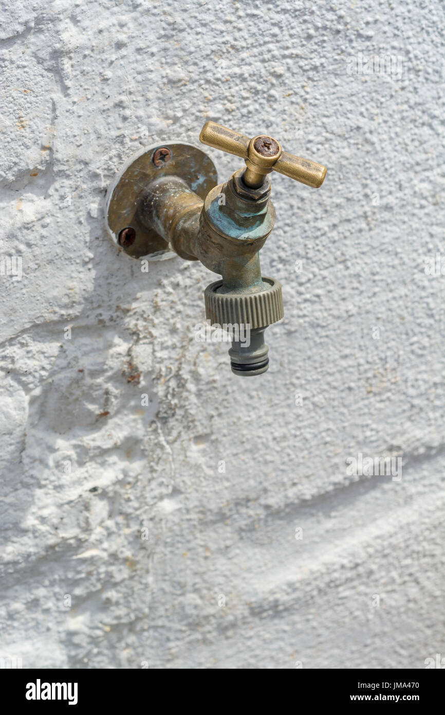 Brass wall tap / garden tap / outside tap seen against whitewashed