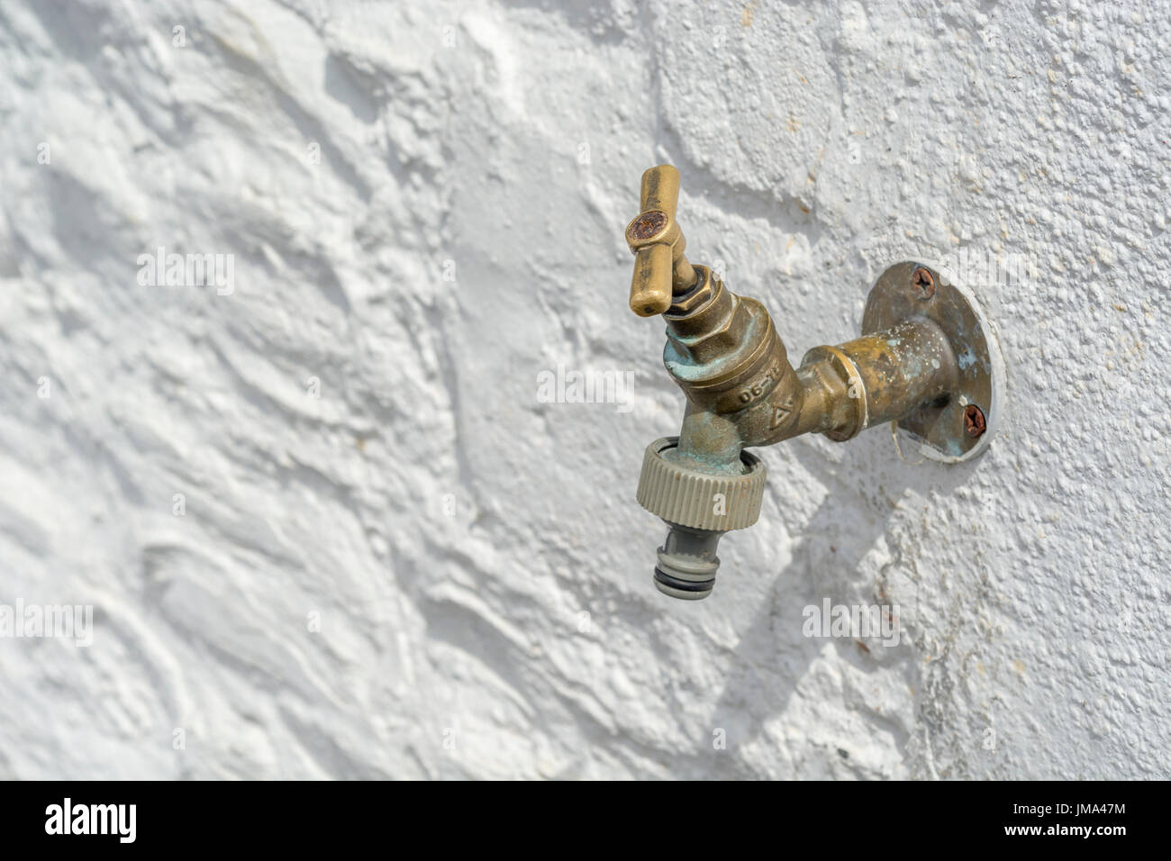 Brass wall tap / garden tap / outside tap seen against whitewashed