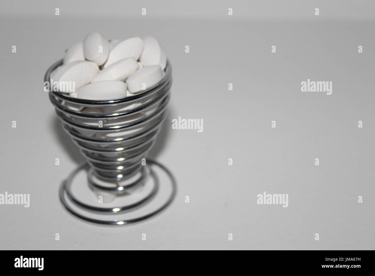 White pills in spiralled egg cup Stock Photo