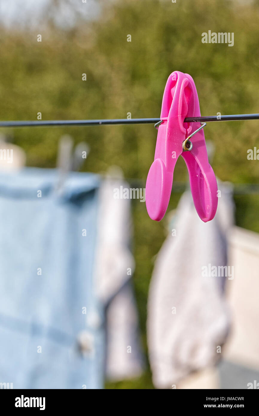 Bright colored towels pegged to a washing line drying against a blurred tree background Stock Photo