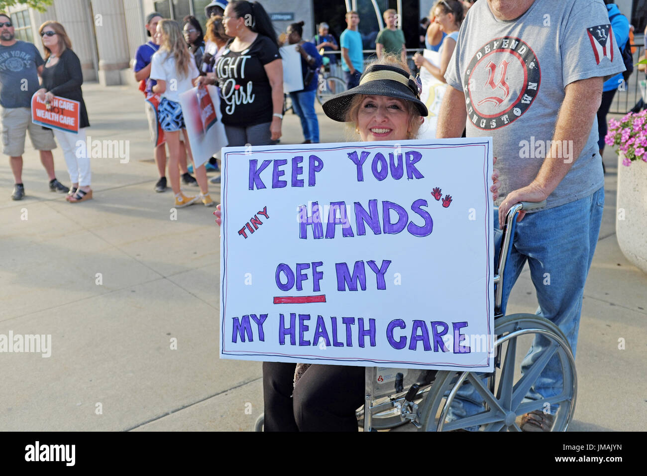 Youngstown, Ohio, USA. 25th July, 2017. Wheelchair bound protester demonstrates against Trumpcare streetside during a visit to the city by President Trump. Credit: Mark Kanning/Alamy Live News Stock Photo