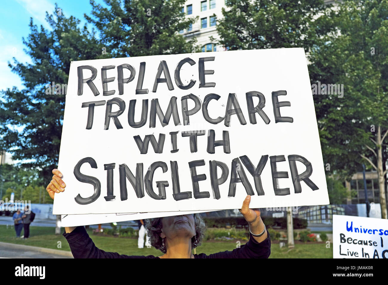 Youngstown, Ohio, USA. 25th Jul, 2017. 'Replace Trumpcare with singlepayer system' is one woman's public protest sign held up on a street corner on an evening that President Trump was visiting the city for a political rally. Credit: Mark Kanning/Alamy Live News Stock Photo