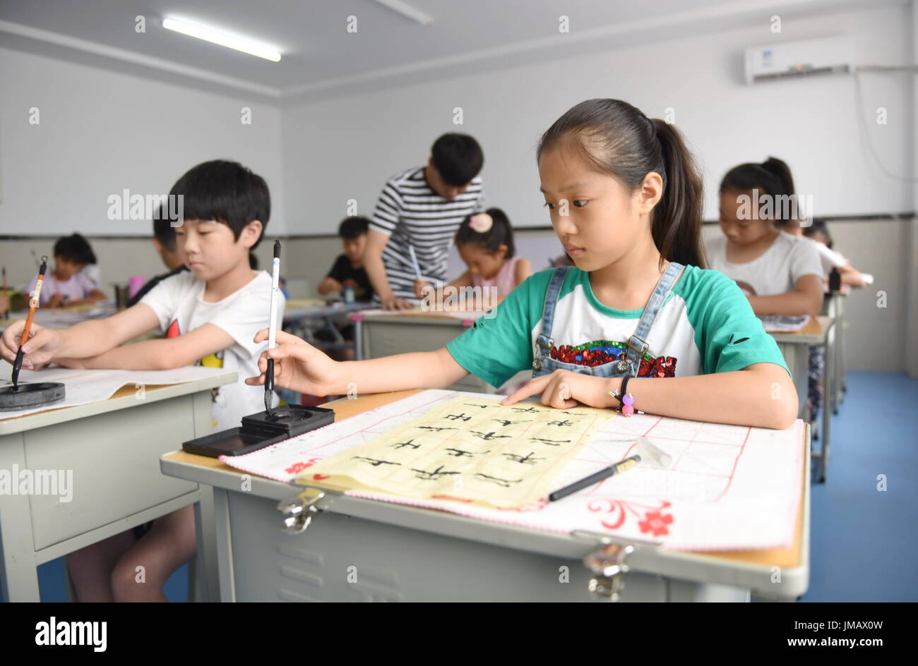 Xingtai. 27th July, 2017. Kids learn calligraphy at the Youth Centre in Nanhe County of north China's Hebei Province, July 27, 2017. During summer vacation, the Nanhe Youth Centre offers various courses for free like dancing, painting, calligraphy to enrich children's life. Credit: Zhu Xudong/Xinhua/Alamy Live News Stock Photo