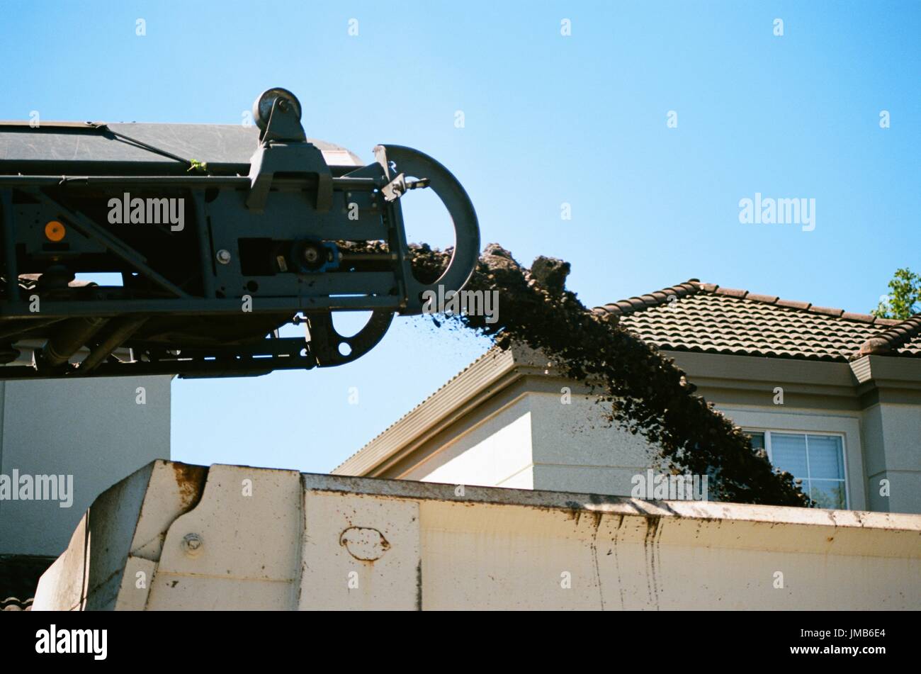 Pulverized asphalt pours from a conveyor belt into a dump truck during a road construction and resurfacing project in the San Francisco Bay Area suburb of San Ramon, California, June 26, 2017. Stock Photo