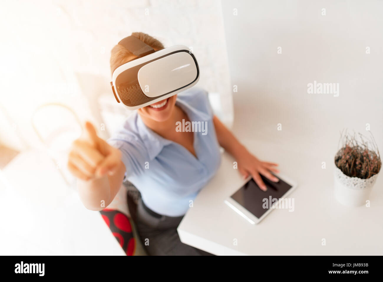 Happy businesswoman using virtual reality glasses in a cafe. Stock Photo
