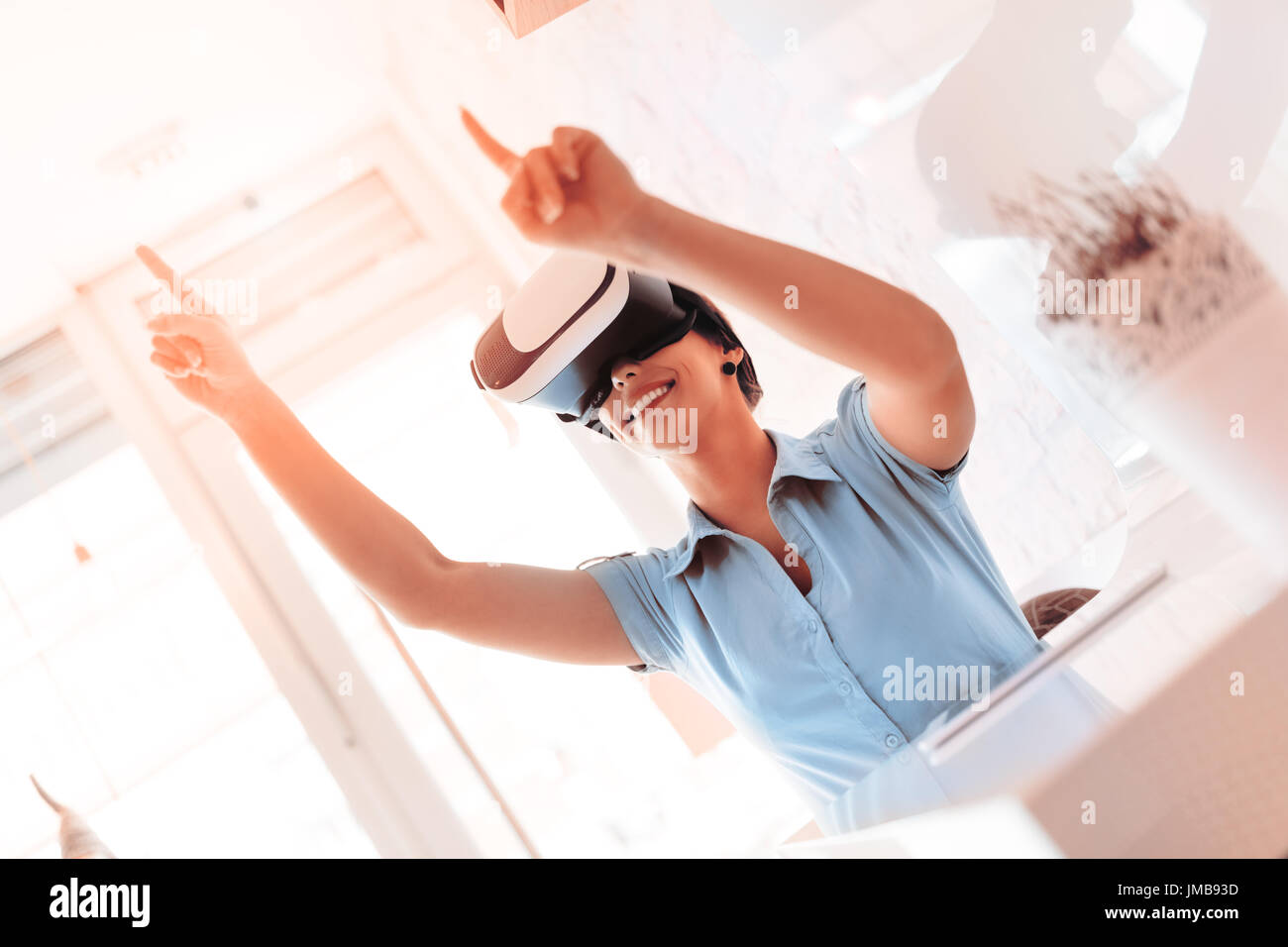 Smiling businesswoman using virtual reality glasses in a cafe. Stock Photo