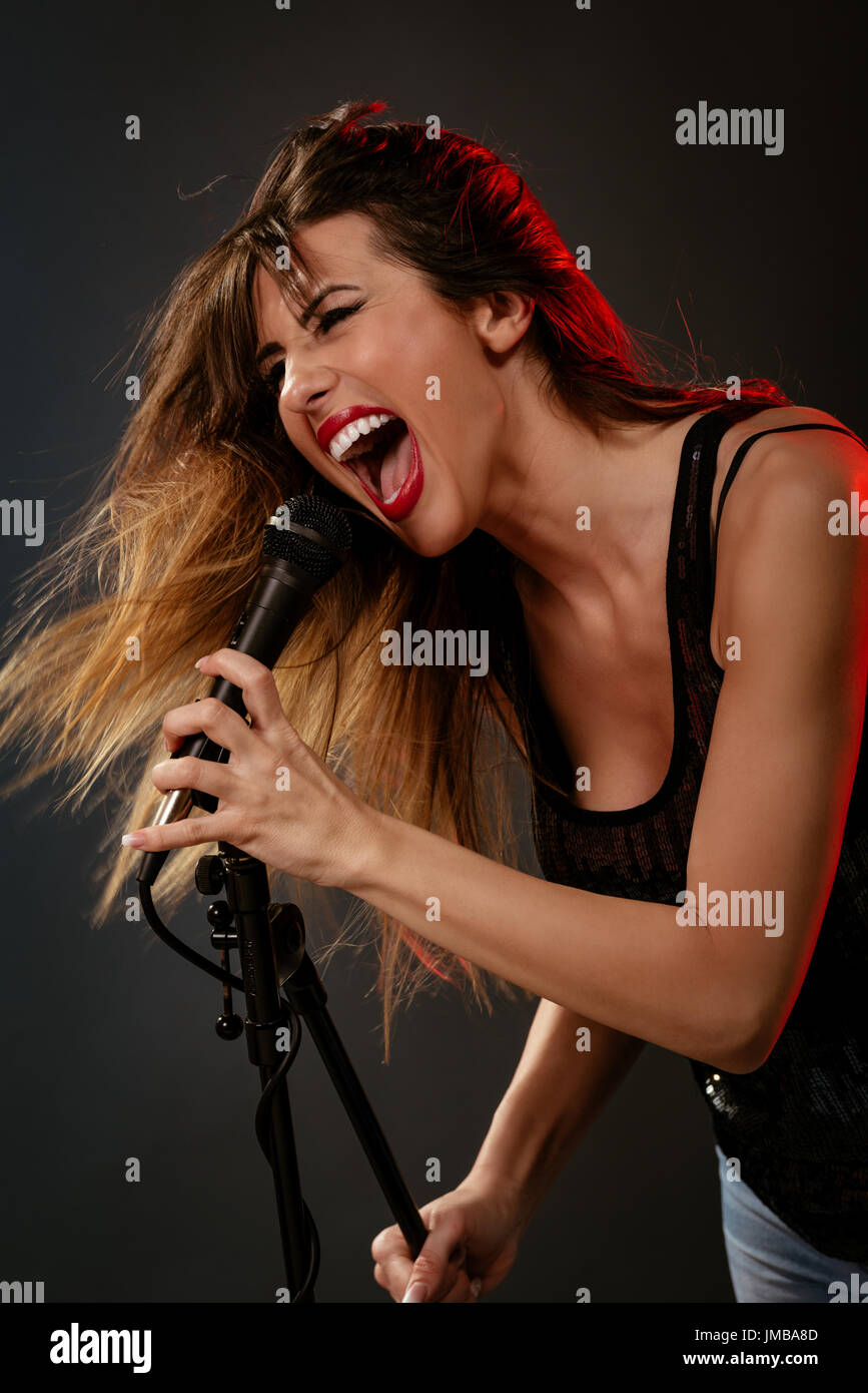 A young woman rock singer with tousled long hair holding a microphone